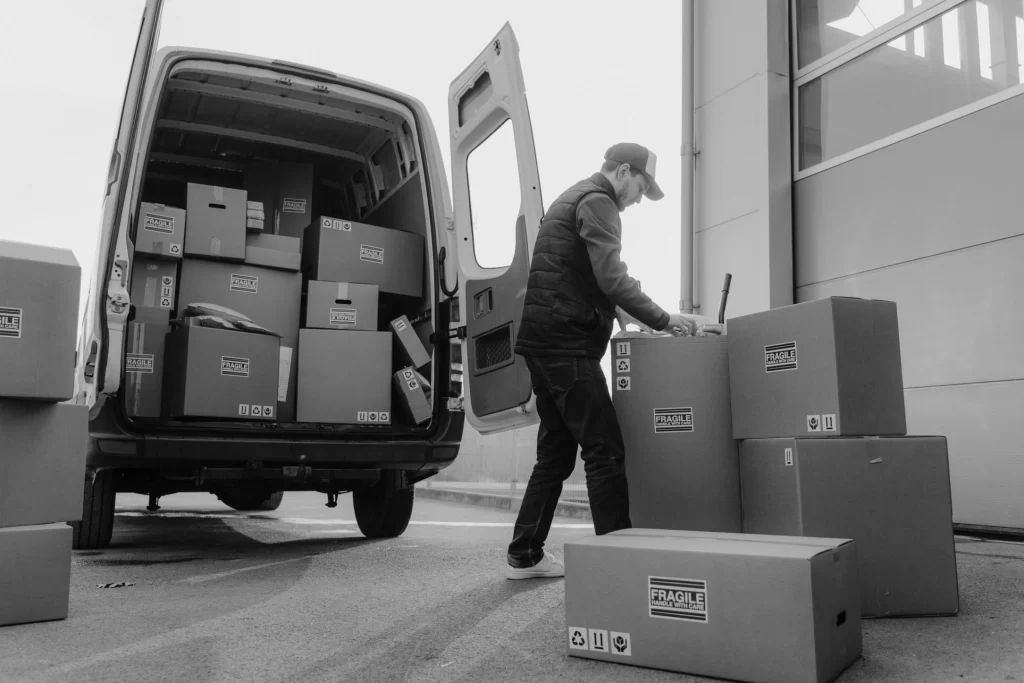 Delivery worker loading fragile packages into a cargo van for commercial transport.