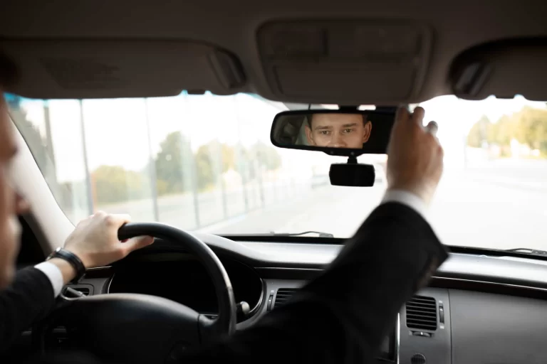 Driver adjusting the rear-view mirror of his car