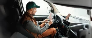 ruck driver inside cabin using a digital tablet for navigation or fleet communication while parked.