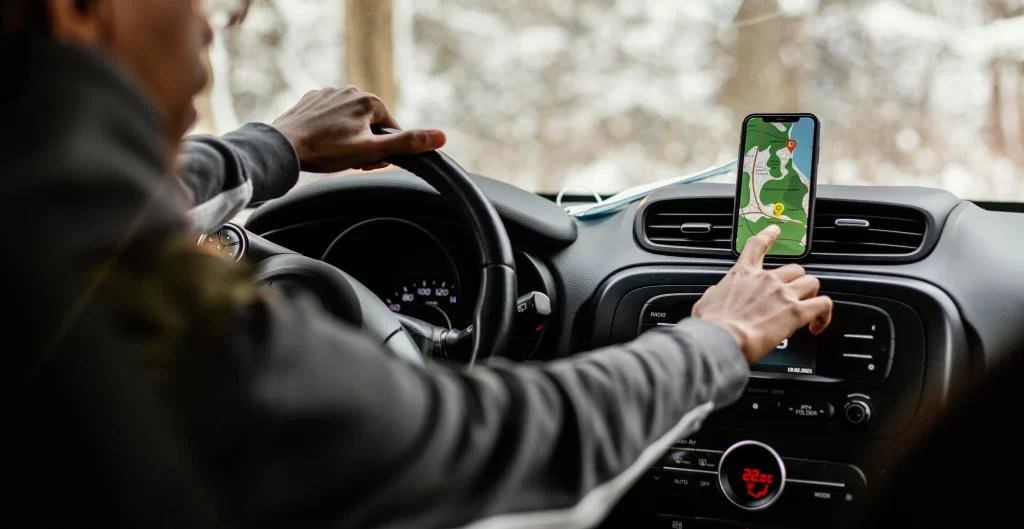 Driver using mobile navigation app mounted on a car dashboard, depicting modern GPS tools for delivery and transportation planning