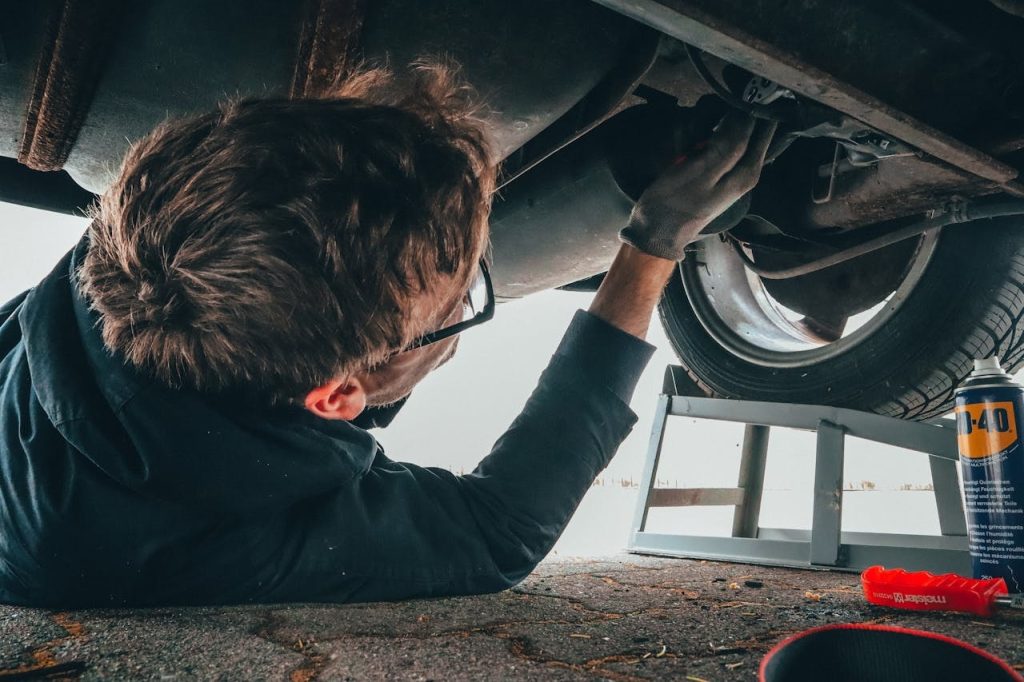 Mechanic performing underbody fleet vehicle maintenance to ensure reliability and safety.