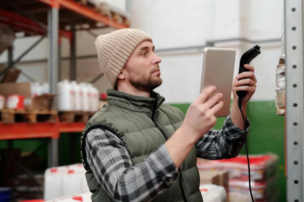 Warehouse worker using a tablet and barcode scanner to track inventory with GPS-enabled system