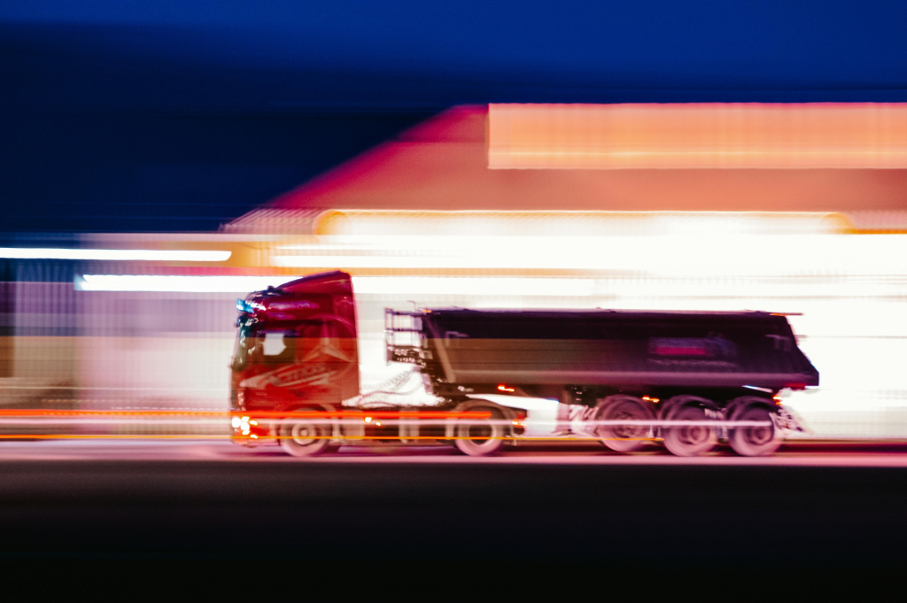 Long-exposure photo of a commercial truck driving at night, symbolizing fleet operations, transportation safety, and driver monitoring.