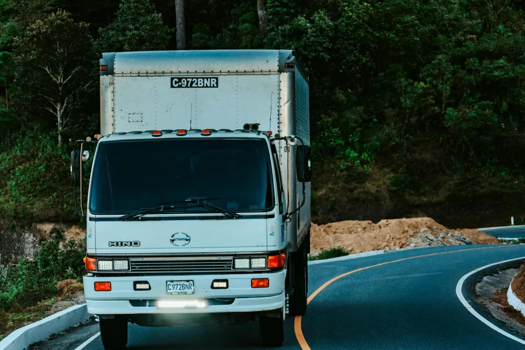 A Hino delivery truck navigating a winding rural road, demonstrating how GPS fleet management helps maintain delivery schedules in challenging terrain.