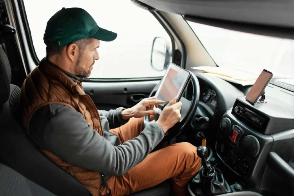 ruck driver inside cabin using a digital tablet for navigation or fleet communication while parked.
